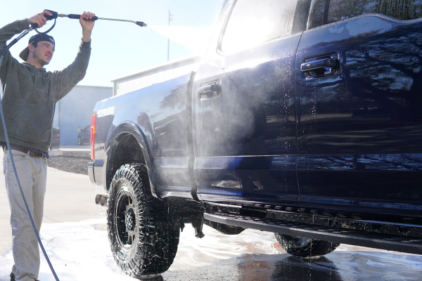 Man spray washing Ford F150 Super Duty during wash